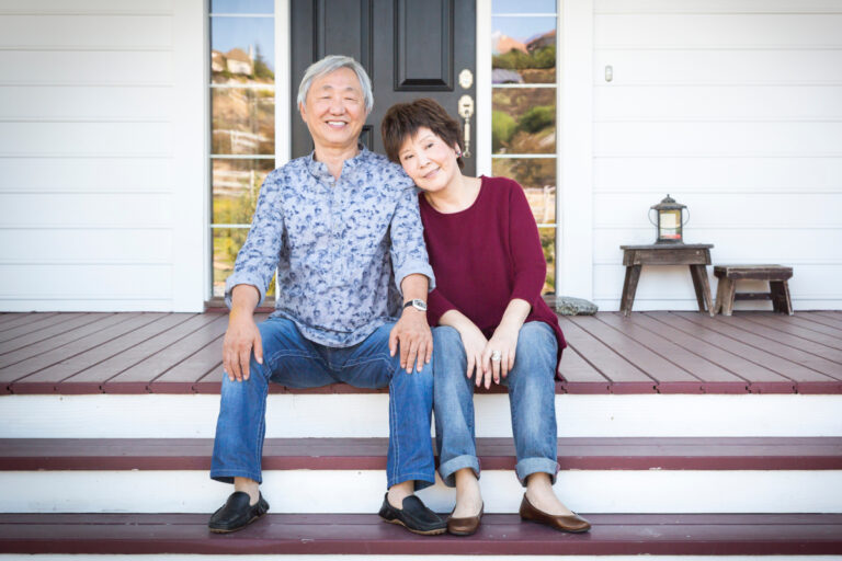 Senior couple smiling outside their home, representing aging in place with confidence