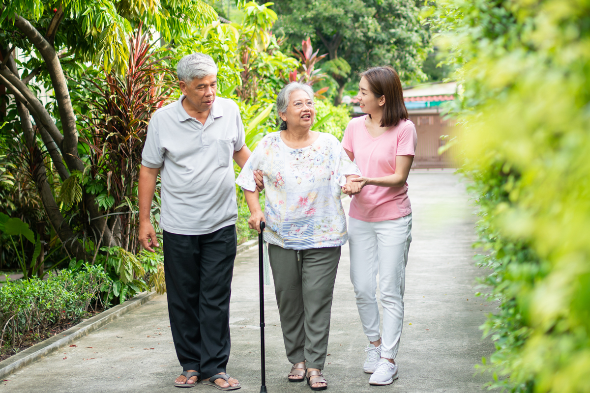 Daughter holding hands with senior mother while touring an assisted living community together