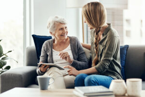 Senior daughter holding hands with elderly mother at home, considering assisted living options